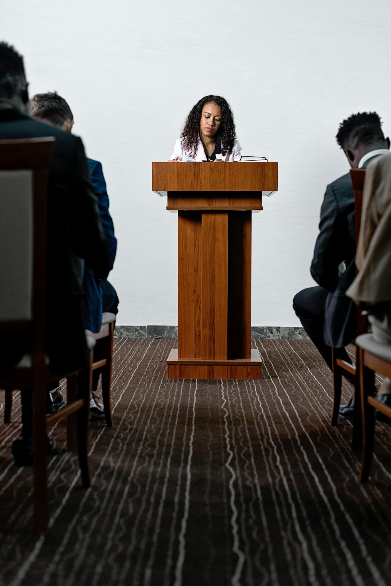 Woman delivering a speech at a conference with attendees seated.