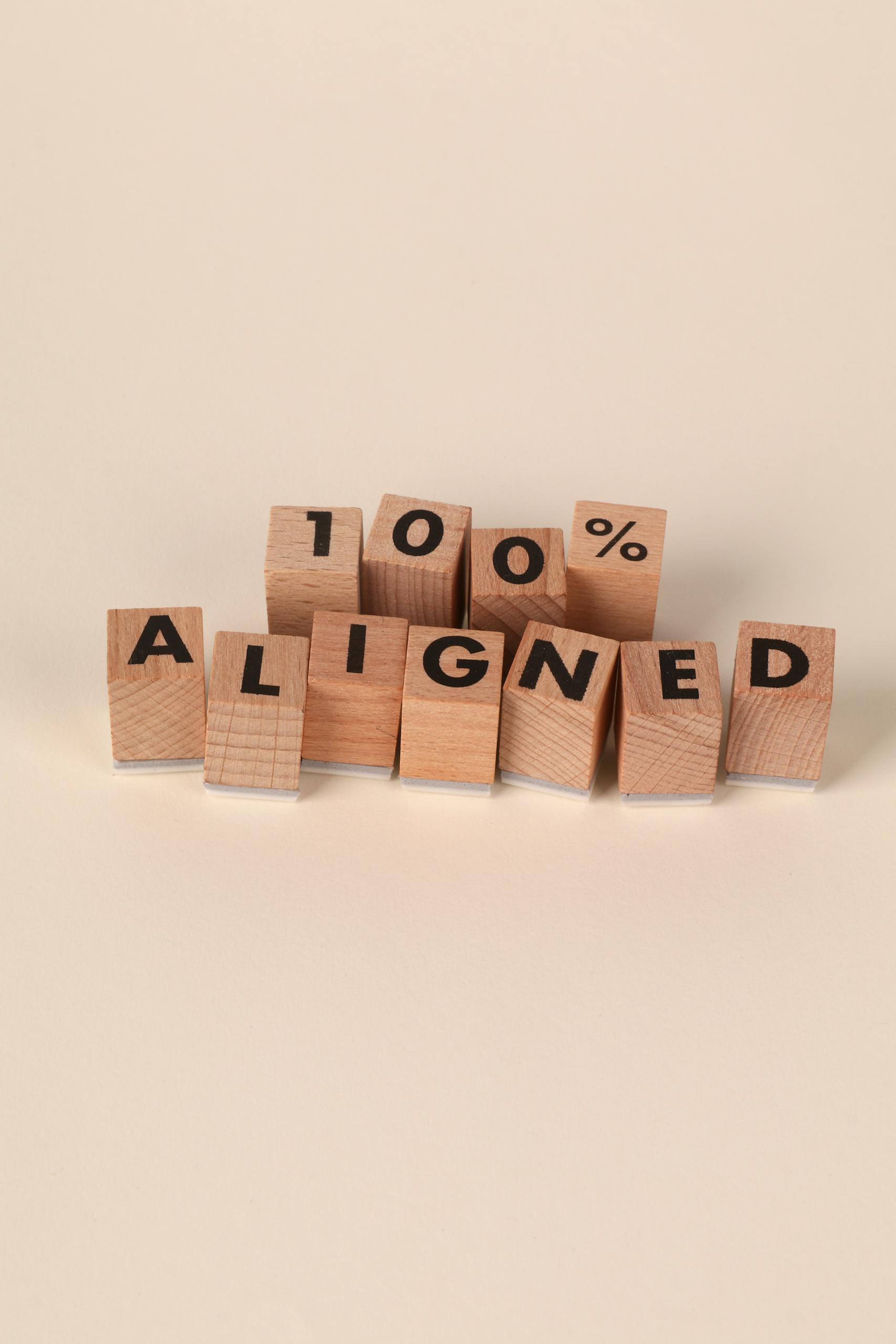 Wooden blocks arranged to spell '100% Aligned,' symbolizing precision and alignment.